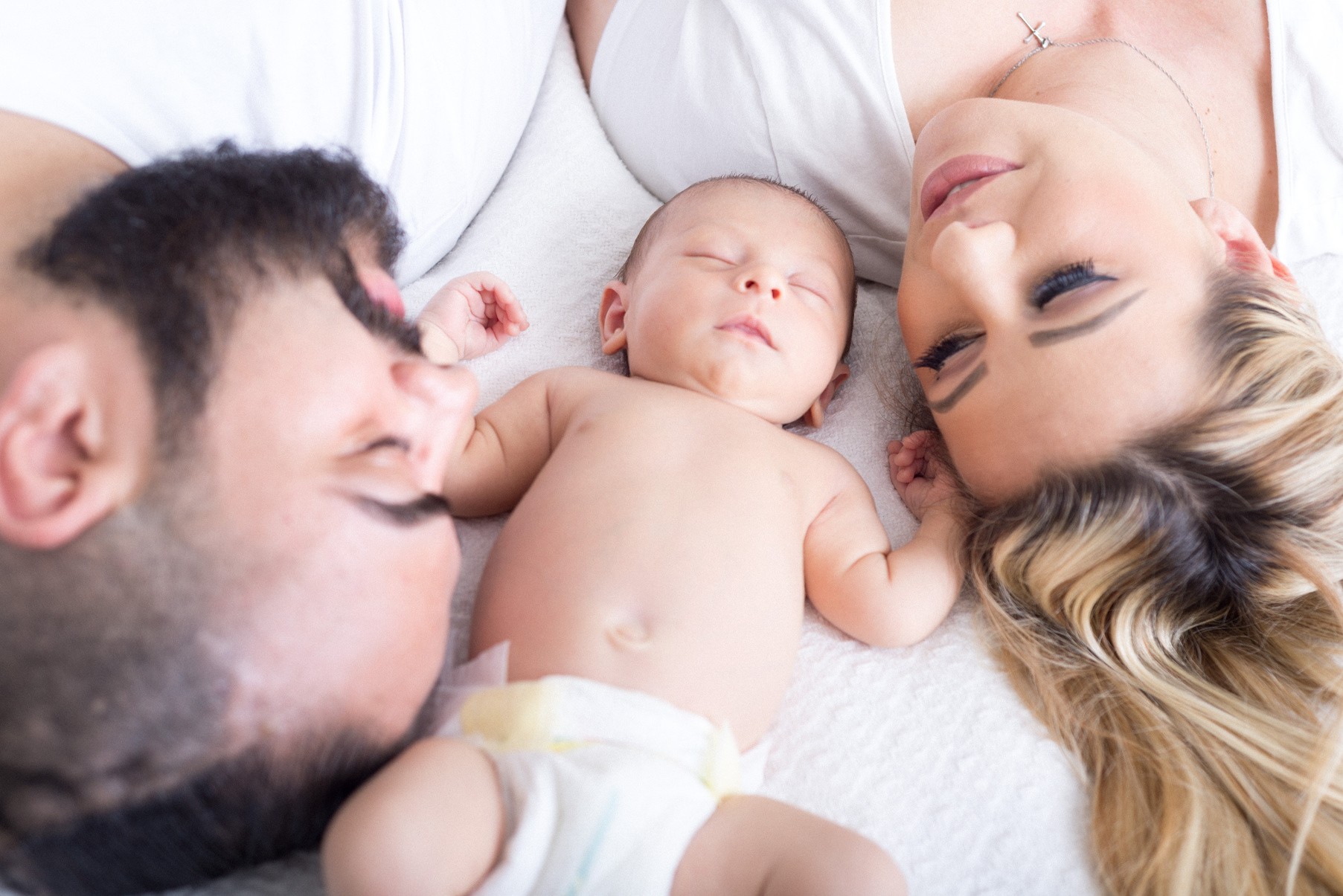 Parents Lying on Bed with Newborn Baby